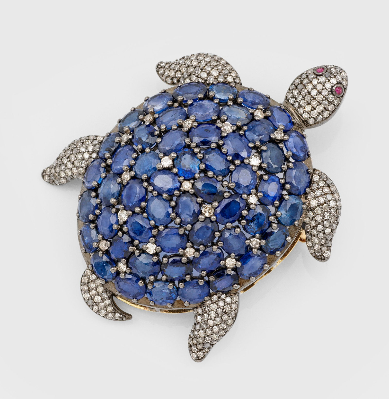 Charmante Schildkrötenbrosche mit Saphiren: Gelbgold und Silber, gest. 56 (584). Ausgefasst mit Saphiren von zus. ca. 13,00 ct. und kleinen Altschliffdiamanten sowie Rubinen. Gew. ca. 19,78 g. Tortoise brooch set with sapphires approx. 13 ct., 