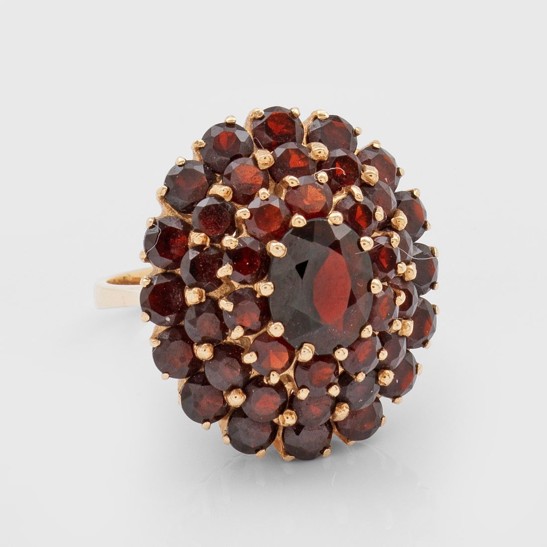 Böhmischer Granat-Ring: Gelbgold, gest. 585. Rosettenförmiger Ringkopf, in gestufter Anordnung besetzt mit tiefroten Granaten von zus. ca. 5,00 ct.; Gew. ca. 10,14 g. Ring set with red garnets approx. 5,00 ct., in 14 k gold