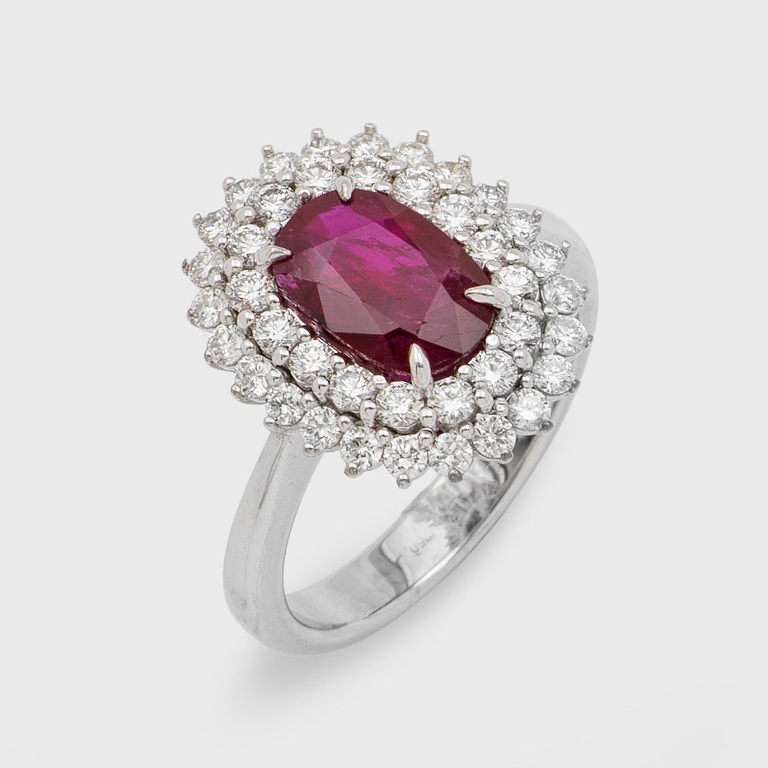 Klassischer Brillant-Entouragering mit Rubin: Weißgold, gest. 750. Zentral besetzt mit einem taubenblutrotem Rubin von ca. 2,32 ct. im Ovalschliff, entouriert von Brillanten von zus. ca. 0,99 ct.; Gew. ca. 6,95 g. Beiliegend Expertise. Ring set 