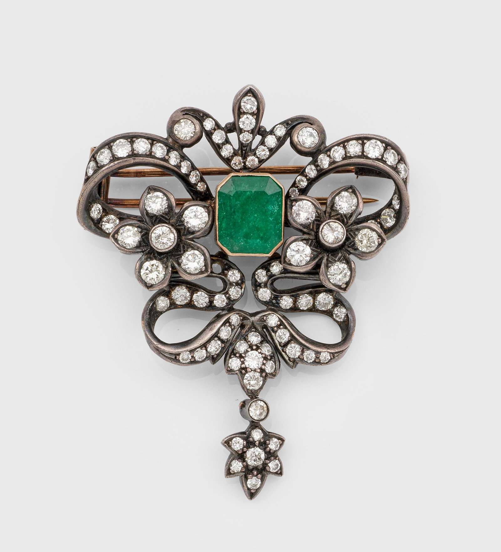 Belle Epoque Diamant-Brosche: Silber und Roségold, 14 ct.; Floral gestaltete Kartuschenform, zentral besetzt mit einem Smaragd von ca. 3,00 ct. und Altschliffdiamanten von zus. ca. 2,00 ct.; Gew. ca. 15,50 g. Brooch set with diam