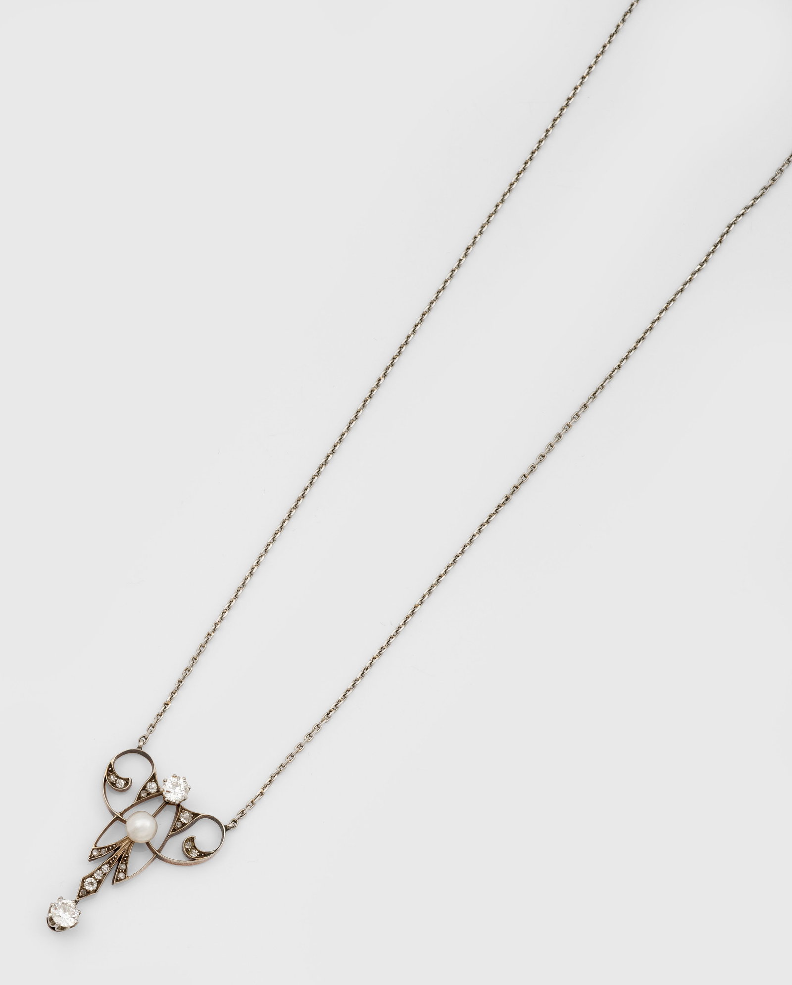 Jugendstil Lavalier-Collier: Platin und Roségold, 14 ct., Kartuschenartig gestalteter Anhänger besetzt mit kleiner Barockperle und Altschliffdiamanten von zus.0,40 ct. in Ajour, an feiner Gliederkette. Ges.-Gew. ca. 8,80 g. Pen