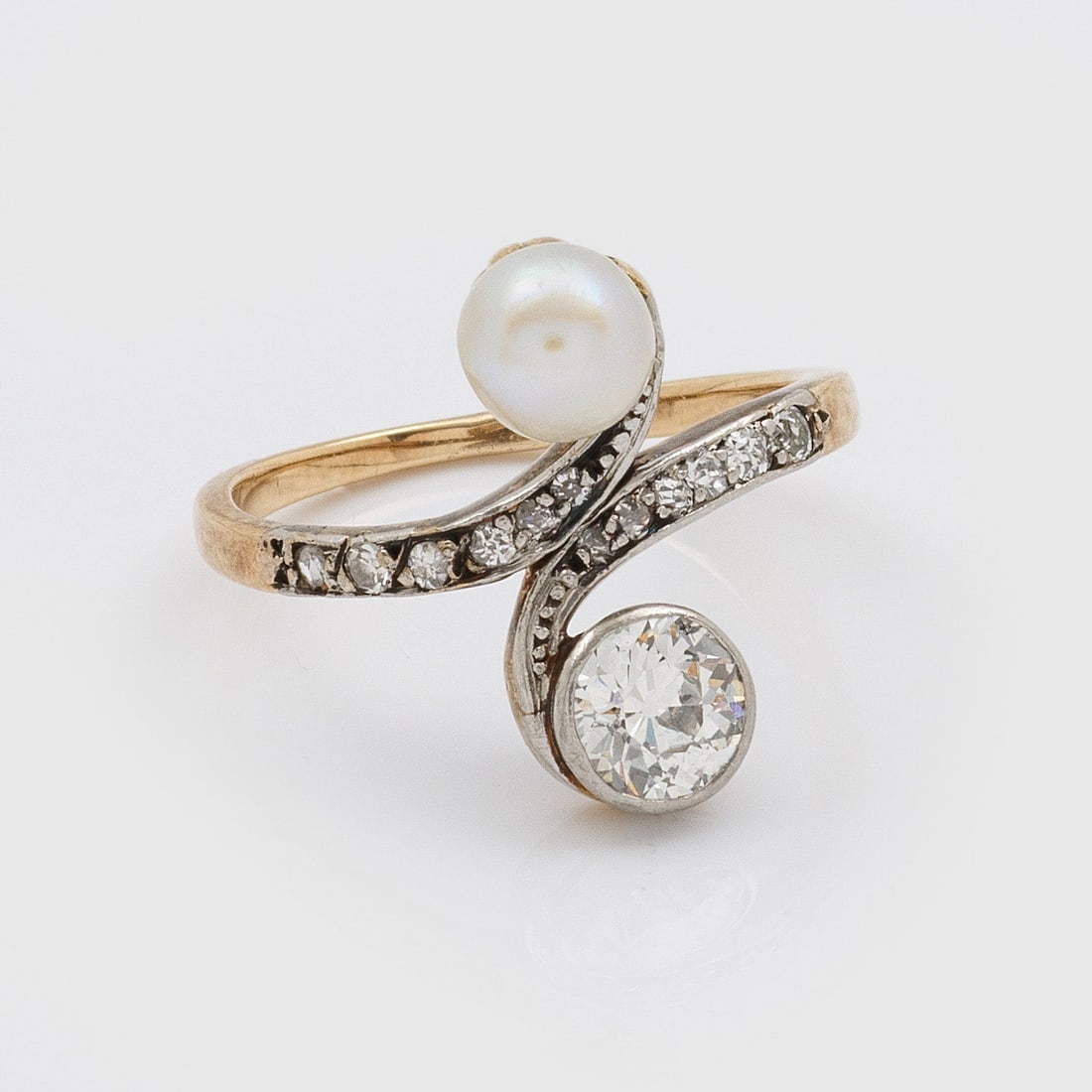 Jugendstil Toi & Moi-Perl-Diamantring: Gelbgold, 14 ct., teilw. platiniert. Diagonal verlaufende Ringschiene besetzt mit kleiner Perle von ca. 5,4 mm und Altschliffdiamanten von ca. 0,60 ct.; Gew. ca. 3,29 g. Ring set with diamond approx. 