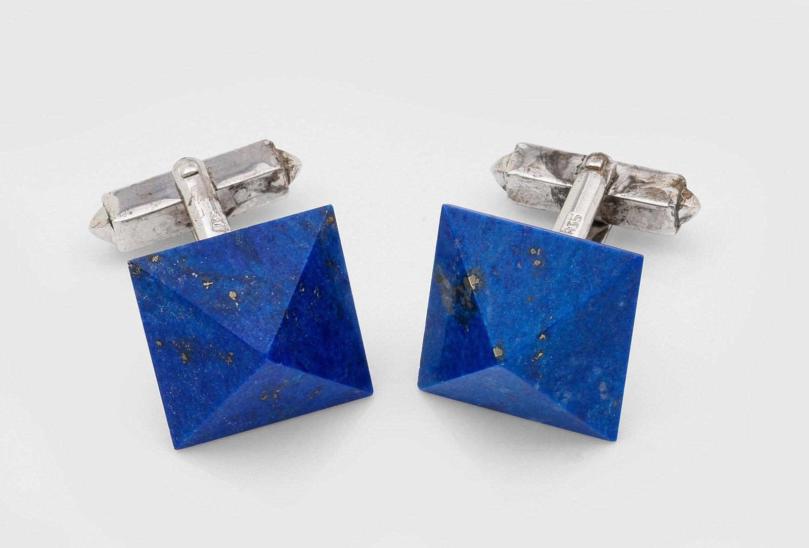 Paar Manschettenknöpfe mit Lapislazuli: Silber, gest. 835. Knöpfe in Form von Pyramiden aus royalblauem Lapislazuli mit feinen Goldeinschlüssen. Ges.-Gew. ca. 12,70 g. Pair of cufflinks set with royal blue lapislazuli with gold inclusions