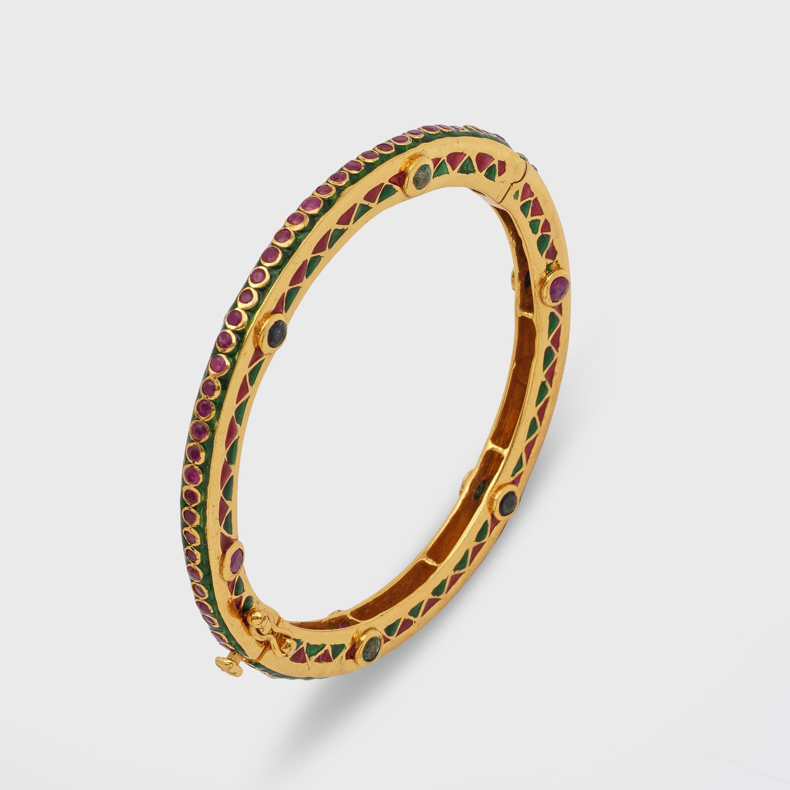 Traditioneller indischer Multicolor-Bangle: Silber, vergoldet, teilw. polychrom emailliert. Ornamentierter Scharnierreif besetzt mit Rubinen, Peridots, grünen Granaten, Mondstein und Amethysten. Gew. ca. 39,10 g. Indian bangle set with rubies,