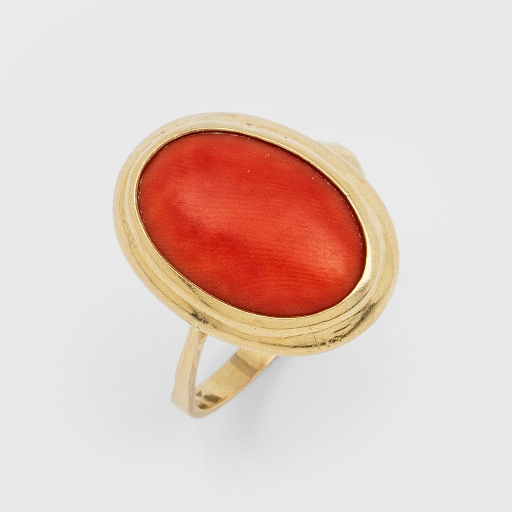 Korallenring aus den 1950er Jahren: Gelbgold, 18 ct.; Zentral besetzt mit lachsfarbenem Korallen-Cabochon. Gew. ca. 5,34 g. Ring set with salmon coloured coral, in 18 k gold.