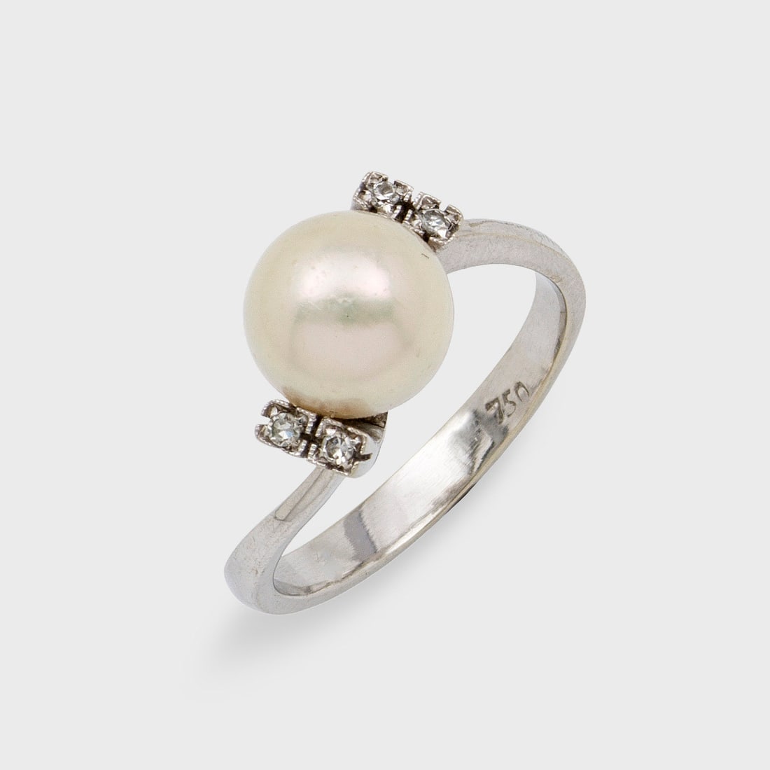 Klassischer Perlen-Ring: Weißgold, gest. 750. Zentral besetzt mit einer cremefarbenen Zuchtperle von ca. 9 mm in sehr feinem, rose-grün changierendem Lüster, flankiert von kleinen Diamanten. 4,47 g. Ring set with a cuture 