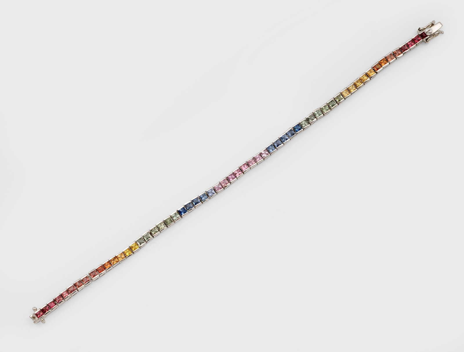 Revière-Armband mit Saphiren in Regenbogen-Skala: Silber, gest. 925. Linear besetzt mit Saphir-Carrées in sog. Regenbogen-Skala. Gew. ca. 9,71 g. Bracelet set with coloured sapphires, in silver.