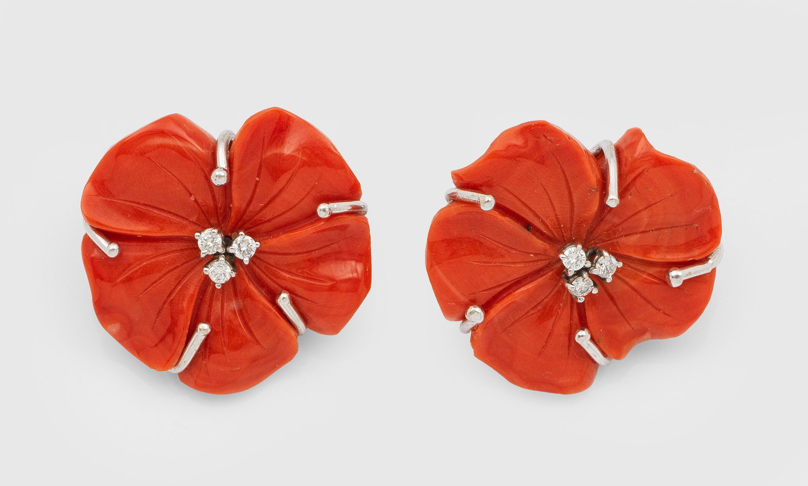Paar charmante Korallen-Ohrclips: Weißgold, gest. 750. Lachsfarbener Korall in Form von Büten geschnitzt, akzentuiert durch kleine Brillanten. Ges.-Gew. ca. 15,95 g. Pair of ear clips set with coral and small diamonds, in 18 k white