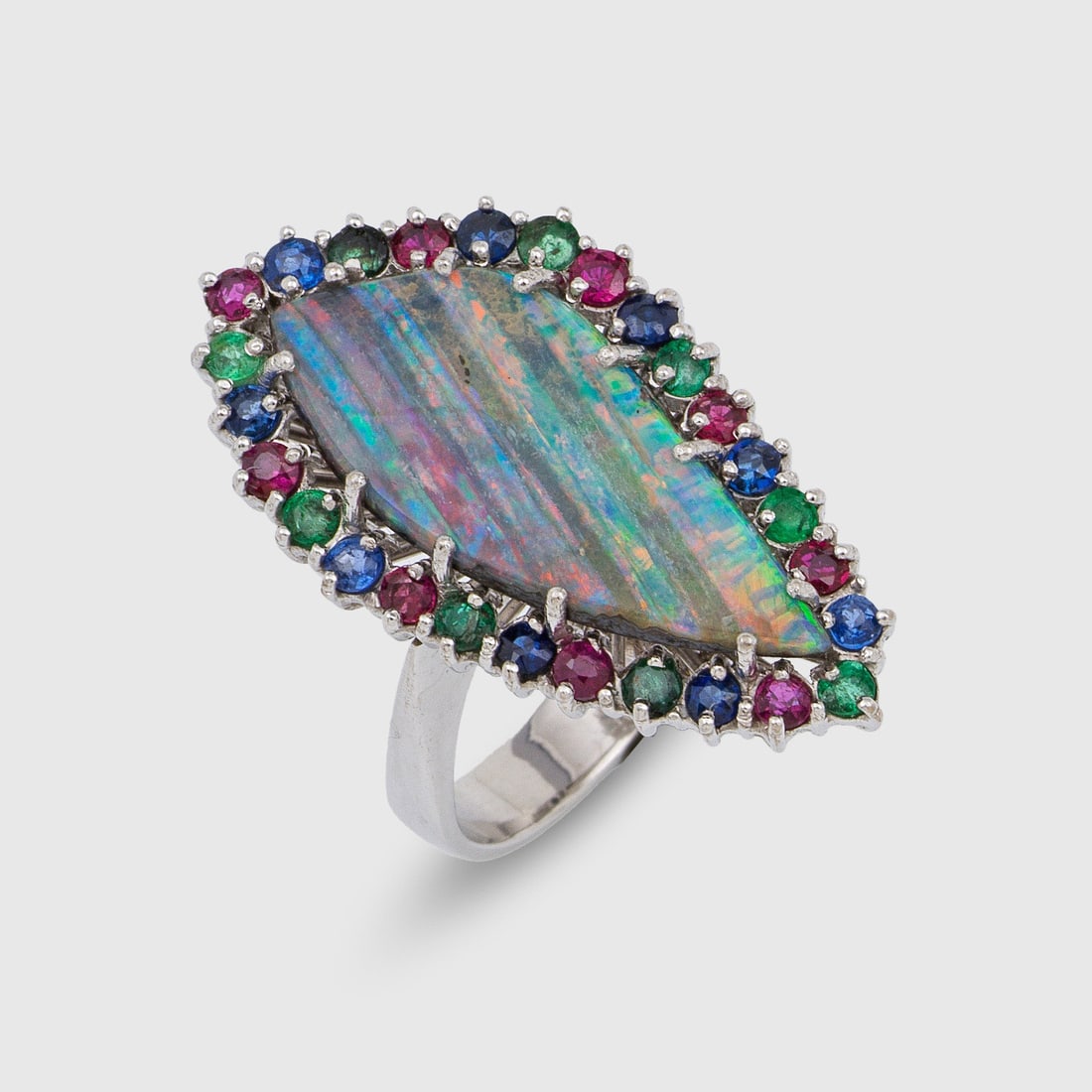 Marquisering mit Honduras-Opal: Weißgold, gest. 750. Zentral besetzt mit einem Opal-Cabochon in sehr schönen, farbenprächtigen Regenbogen-Farben, entouriert von kleinen Rubinen, Saphiren und Smaragden. Gew. ca. 11,84 g. Ring set 