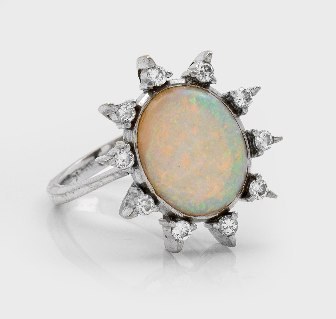 Opal-Brillantring: Weißgold, 14 ct.; Zentral besetzt mit einem Weißopal-Cabochon in sehr schönem Farbspiel, entouriert von Brillanten von zus. ca. 0,30 ct.; Gew. ca. 5,42 g. Ring set with a white opal and diamonds ap