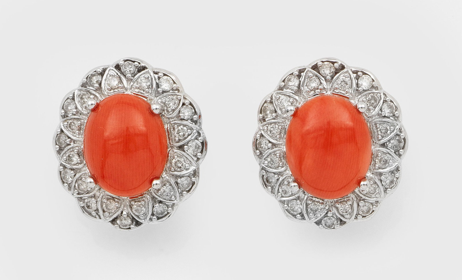 Paar elegante Korallen-Ohrclips: Weißgold, gest. 585. Zentral besetzt mit 2 lachsfarbenen Korallen-Cabochons von ca. 11 x 9 x 5 mm, entouriert von kleinen Diamanten. Gew. ca. 8,55 g. Ring set with 2 red corals approx. 11 x 9 x 5 mm