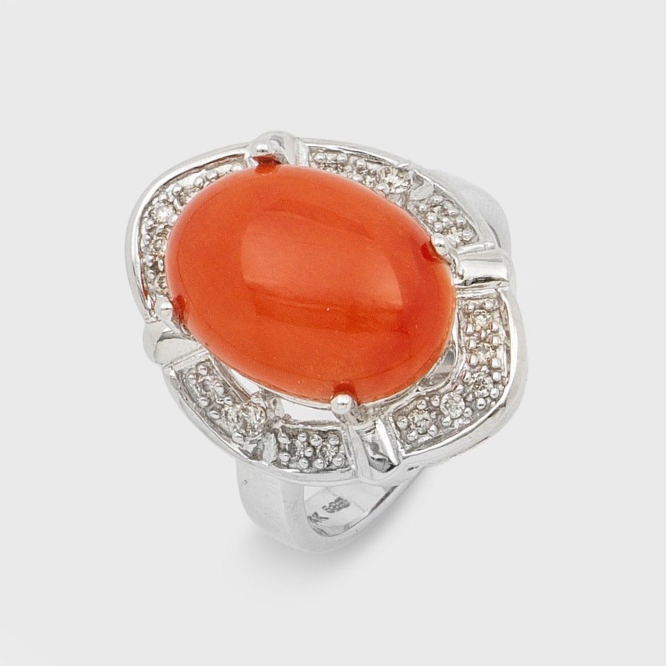 Eleganter Korallenring: Weißgold, gest. 585. Zentral besetzt mit einem lachsfarbenen Korallen-Cabochon von ca. 14 x 11 x 7 mm, entouriert von kleinen Diamanten. Gew. ca. 7,21 g. Ring set with a red coral approx. 14 x 11 x