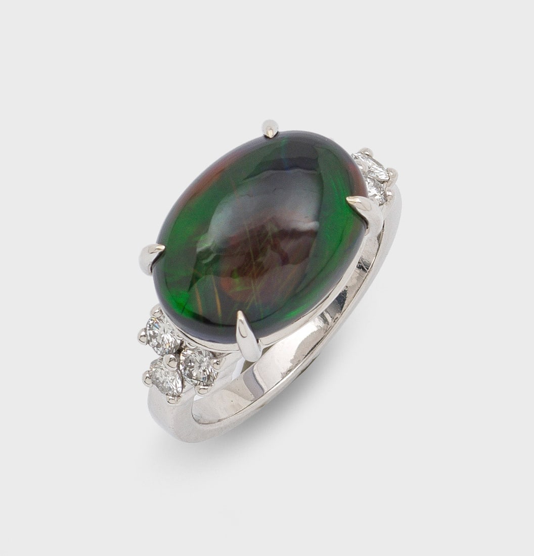 Opal-Brillantring: Weißgold, gest. 585. Zentral besetzt mit einem Opal-Cabochon mit grün-orangenem Farbspiel, flankiert von 6 Brillantan von zus. ca. 0,60 ct.; Gew. ca. 6,18 g. Ring set with an opal and diamonds