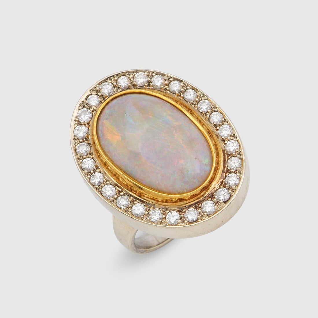 Entourage-Brillantring mit Opal: Weißgold, gest. 585. Zentral besetzt mit einem Opal-Cabochon von sehr feinem Farbspiel, entouriert von Brillanten von zus. ca. 1,00 ct.; Gew. ca. 9,87 g. Ring set with an opal and diamonds approx.