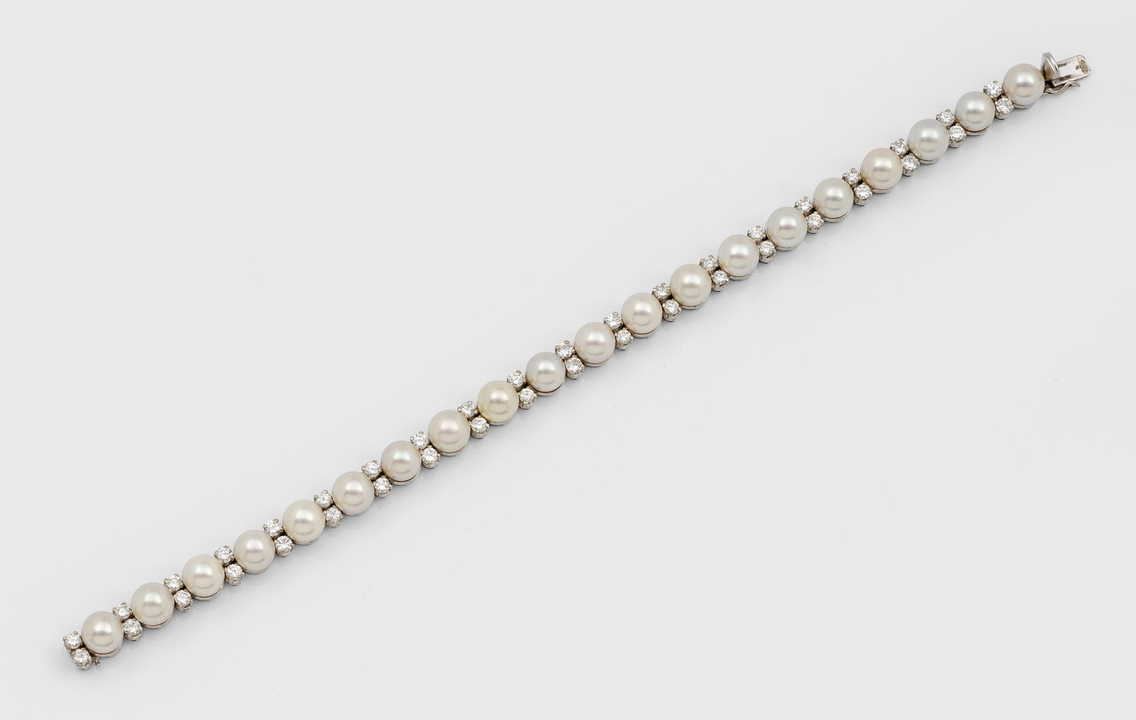 Klassisches Perl-Brillant-Armband: Weißgold, gest. 18 ct.; Linear besetzt mit weißen Zuchtperlen von ca. 6 mm in sehr farbintensivem, rosé-grün changierendem Lüster, unterteilt durch Brillanten von zus. ca. 1,40 ct. (H-I/vs-si).