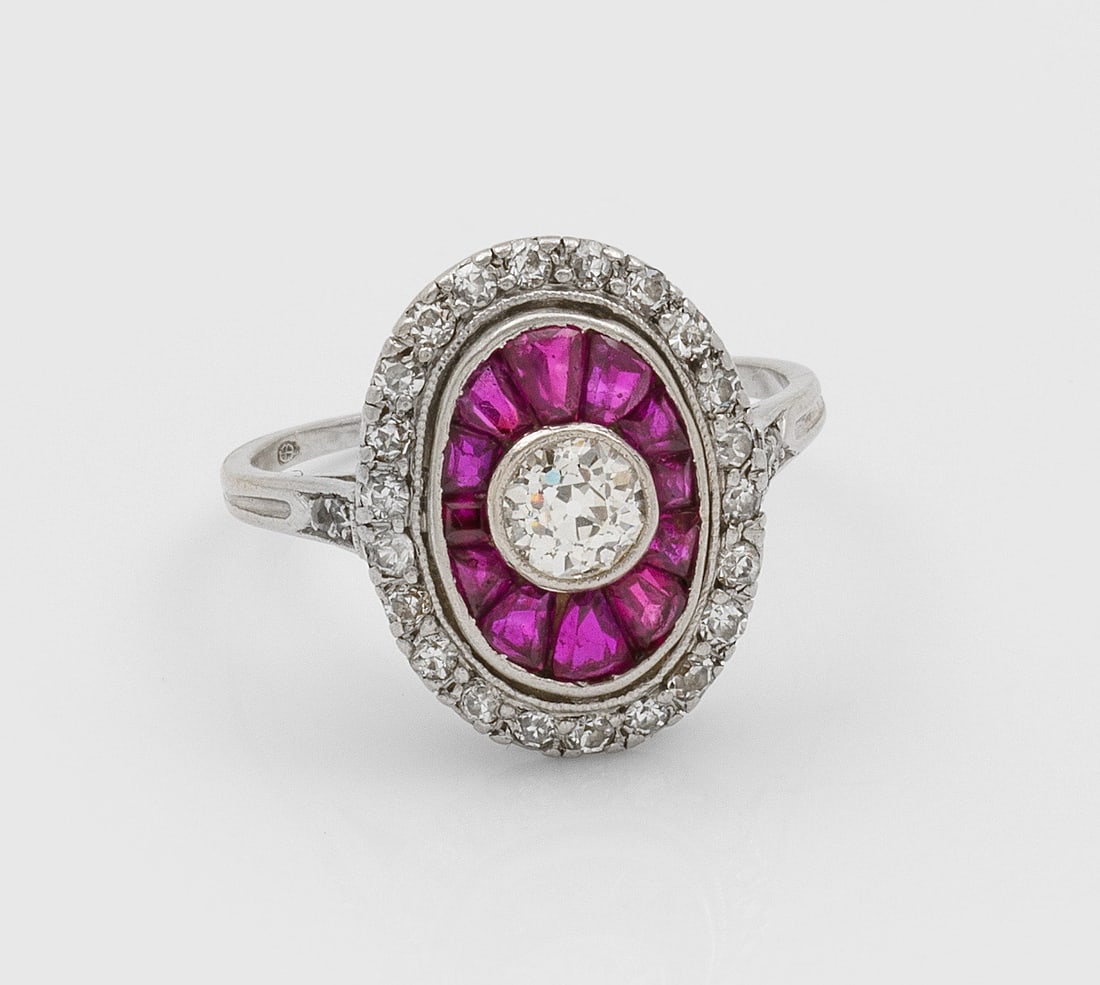 Art Déco Rubin-Diamantring: Platin. Medaillonförmiger Ringkopf besetzt mit einem Altschliffdiamant von ca. 0,25 ct., fächerartig umrandet von taubenblutroten Rubinen und kleinen Diamaten. Gew. 3,89 g. Ring set with a diamond a