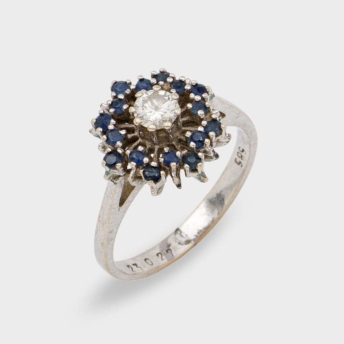 Saphir-Brillantring: Weißgold, gest. 585. Blütenförmiger Ringkopf zentral besetzt mit einem Brillant von ca. 0,20 ct., umrahmt von kleinen Saphiren. Gew. ca. 3,55 g. Ring set with a diamond approx. 0,20 ct. and small s