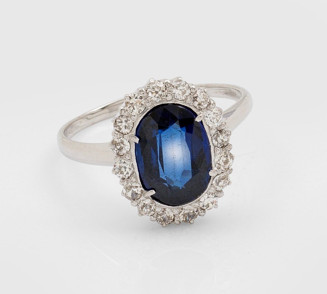 Klassischer Saphir-Diamantring: Weißgold, 14 ct.; Zentral besetzt mit Saphir von ca. 2,00 ct. im Ovalschliff, entouriert von Altschliffdiamanten von zus. ca. 0,80 ct.; Gew. ca. 4,11 g. Ring set with sapphir approx. 2,00 ct. and