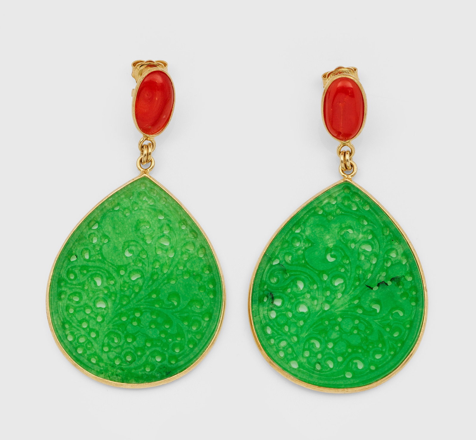 Paar dekorative Jade-Pendeloques: Silber, vergoldet. Schauseitig besetzt mit spinatgrüner Jade in floraler Ajourarbeit und roten Korallencabochons. Ges.-Gew. 7,90 g. Pair of earrings set with coral and jade, in silver gilded.