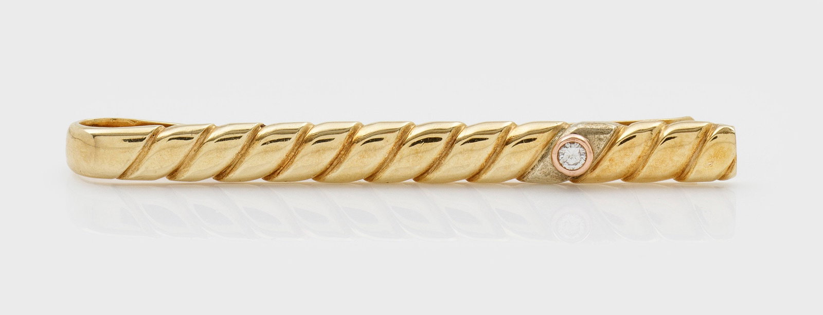 Krawattennadel mit Brillantsolitär: Gelbgold, gest. 585. Schauseitig Kordelbanddekor, akzentuiert durch Brillanten von ca. 0,05 ct.; Gew. ca. 5,41 g. Tie clip with brilliant solitaire approx. 0,05 ct., in 14 k gold.