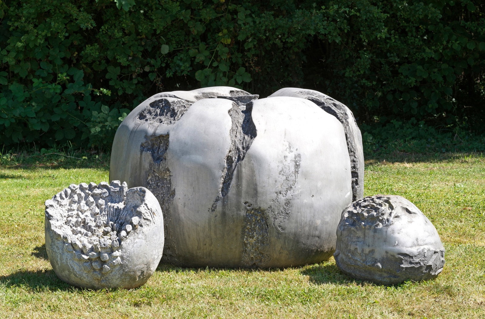 Modernes Wasserspiel: 4-tlg.; Grauer Stein. Oval gedrückte, teilw. aufgebrochene und durch Reliefstrukturen geformte sowie unterschiedlich große und vertiefte Körper. Bogenförmig begrenzender Metallrahmen. H. ca. 40 cm