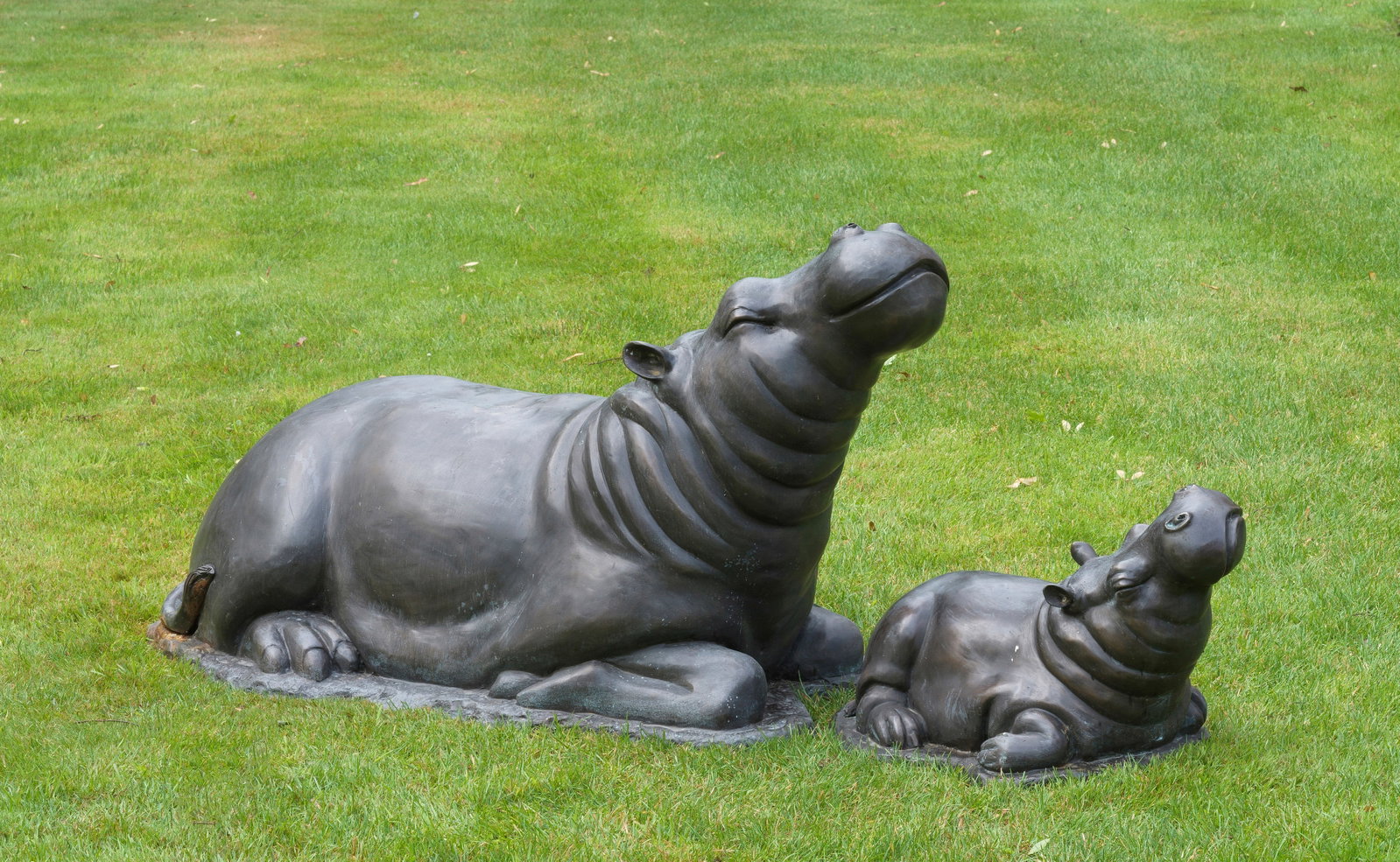 Paar Brunnenplastiken in Gestalt eines Nilpferds: Bronze, dunkel patiniert. Vollpastische und naturgetreue Darstellung eines kleinen Jung- und eines großen Muttertieres in entspannt liegender Haltung, das Haupt des Flusspferds mit erfülltem Ausdruc