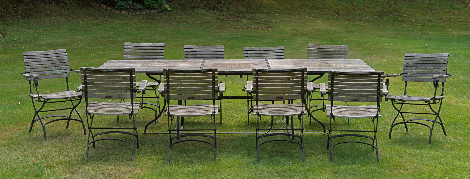 Großer Gartentisch mit zehn Armlehnenstühlen von Garpa: "Fontenay" von Garpa Plantagenteak und Eisen. Schwarz lackiertes, scherenförmiges Gestell, die Sitzfläche durch schmale Streben verbrettert. Großer, rechteckiger, korrespondierender Tisch mit zusä