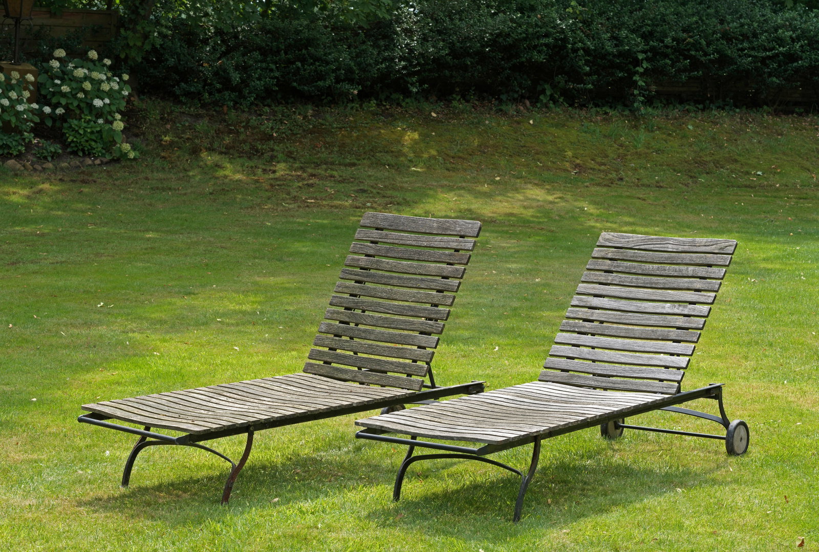 Paar Gartenliegen "Fontenay" von Garpa: Plantagenteak und Eisen. Längsrechteckige Form. Schwarz lackiertes Gestell mit Querstreben bebrettert, Hersteller-Plaketten. Witterungsspuren und Patina. L. ca. 205 cm. A pair of German garden lounge