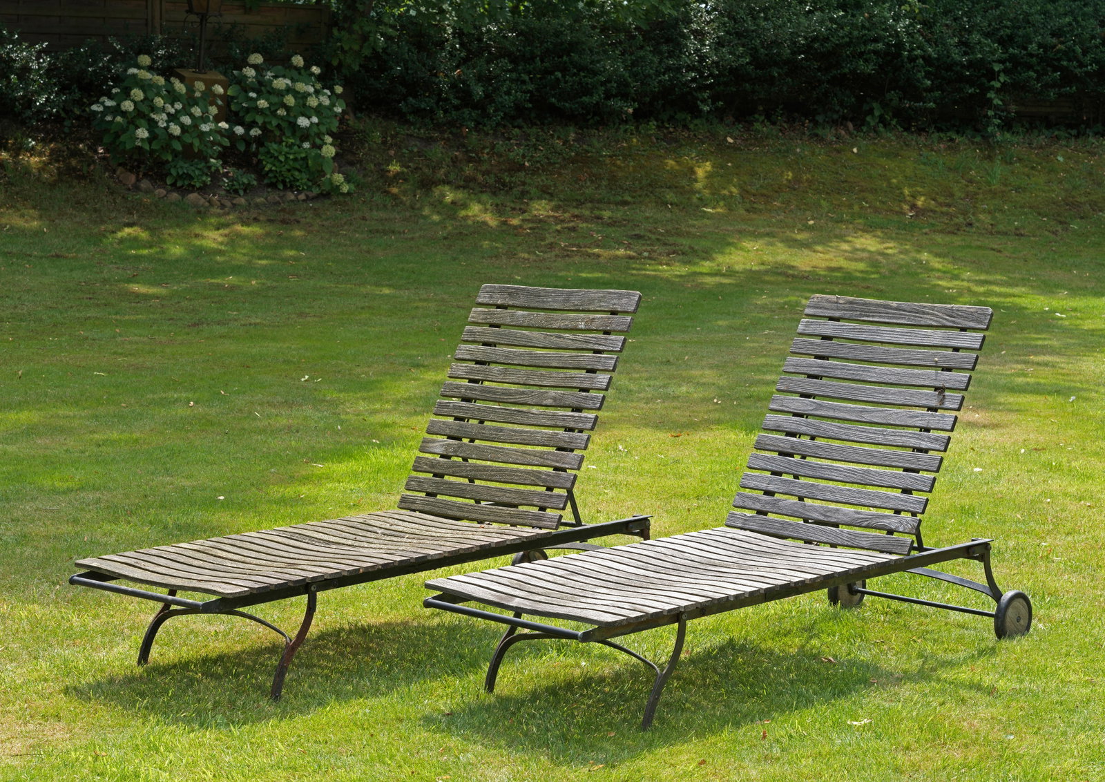 Paar Gartenliegen "Fontenay" von Garpa: Plantagenteak und Eisen. Längsrechteckige Form. Schwarz lackiertes Gestell mit Querstreben bebrettert, Hersteller-Plaketten. Witterungsspuren und Patina. L. ca. 205 cm. A pair of garden loungers "Fon