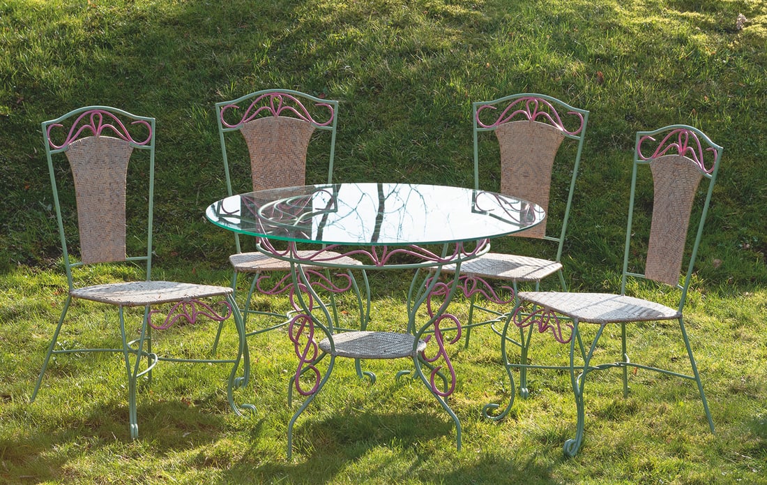 Garnitur Wintergartenmöbel: 5-tlg.; Tisch und vier Stühle. Metall, seegrün und pink lackiert. Gestell aus stark geschwungenen Streben und stilisierten Volutenmotiven mit offen gestalteter Zarge als Träger für runde Deckplatt
