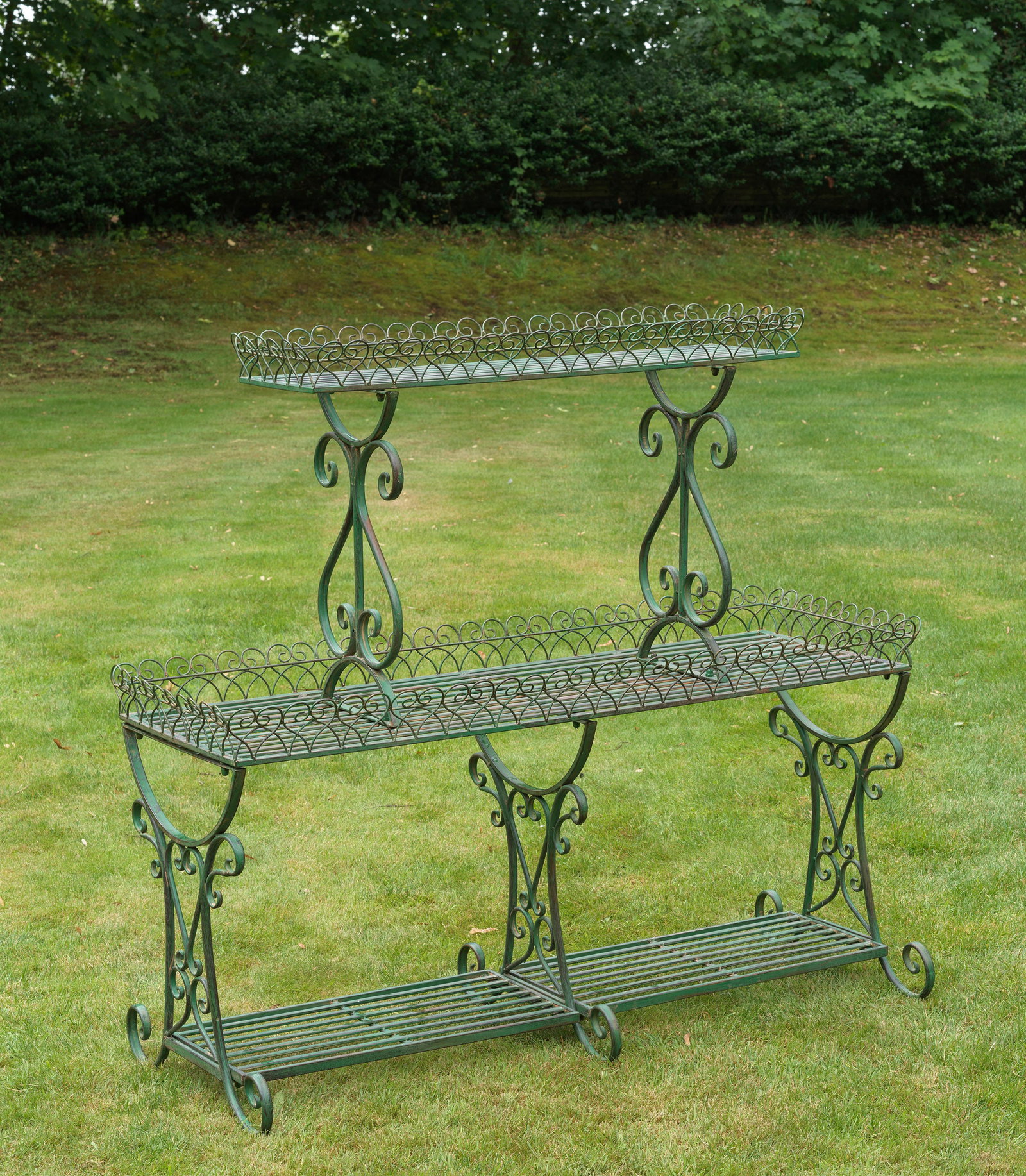 Große Belle Epoque-Blumenetagère: Metall, grün lackiert. Offener, längsrechteckiger, durch Querstreben gegliederter Korpus auf drei Ebenen. Gestell und Rand aus gedrehten, volutenförmig eingerollten und ornamental angelegten Rundst