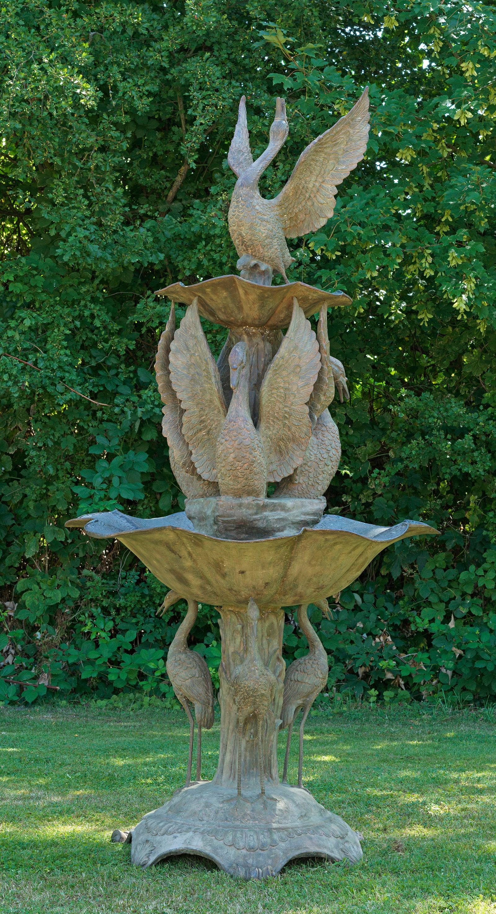 Imposanter Belle Epoque-Parkbrunnen: Bronze, patiniert. Leicht gewölbter, eingezogener Sockel mit Blattvoluten und Zungenfries. Zentral naturalistisch gestalteter Schaft, umringt von stehenden Reihern als Träger für die vertiefte, ged