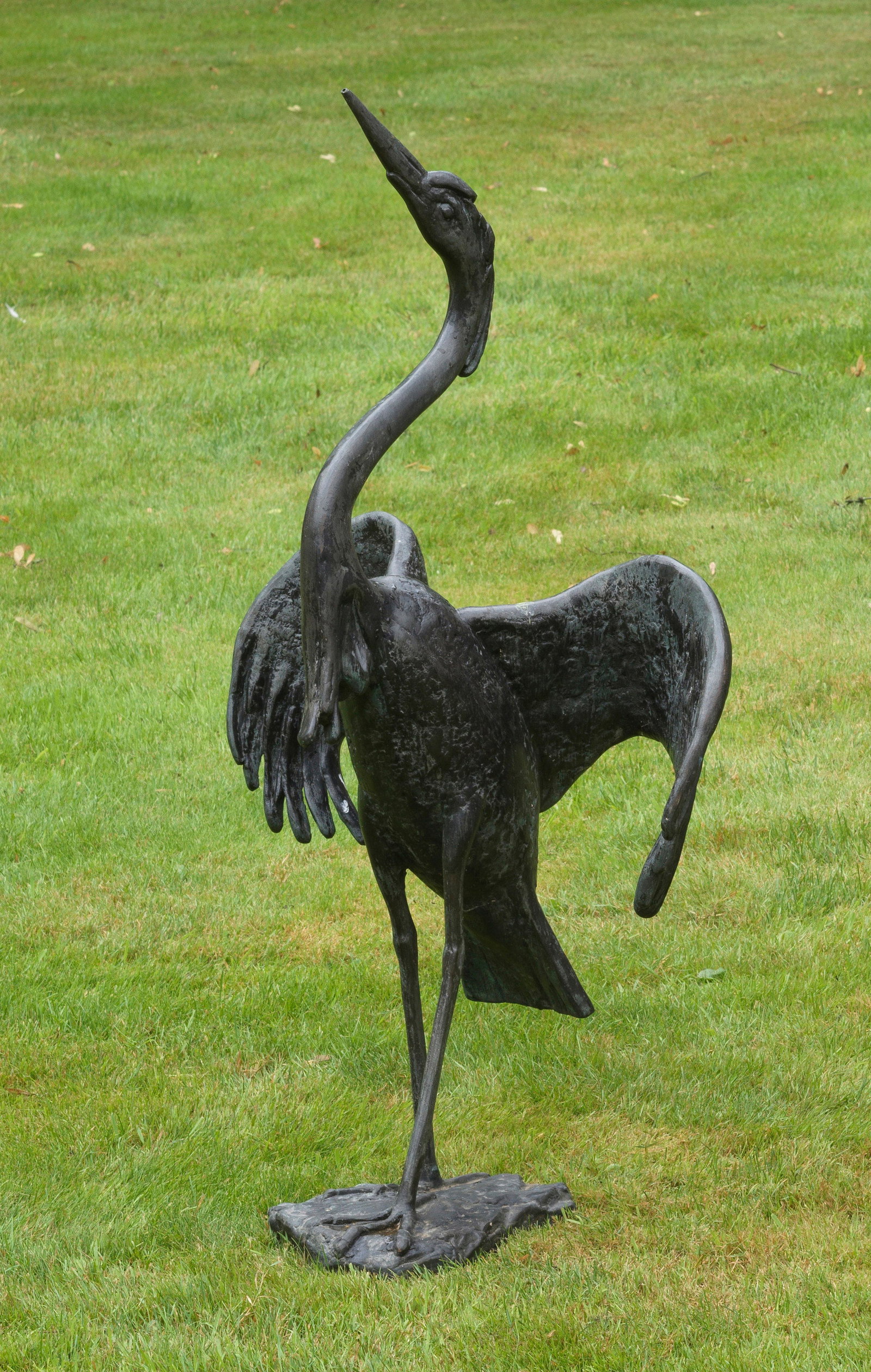 Fischreiher als Gartenfigur: Bronze, dunkel patiniert. Auf flachem, unregelmäßigen Natursockel die vollplastische und naturgetreue Darstellung eines schreitenden, auch als Wasserspeiher konzipierten Reihers mit ausgebreiteten S