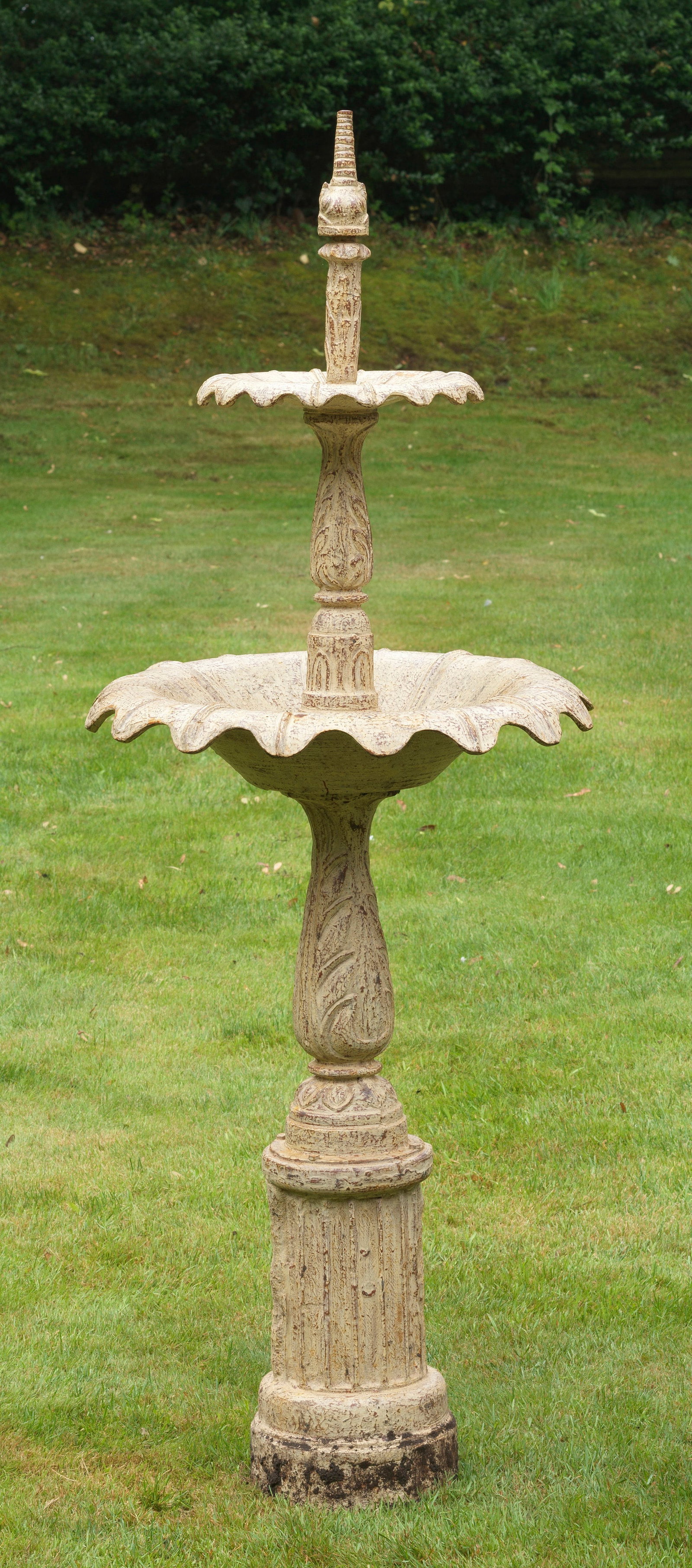 Gartenbrunnen: Gusseisen, cremefarben lackiert. Über profilierter Basis mehrfach gegliederter, sich konisch verjüngender, blattreliefierter Balusterschaft als Träger für zwei gestaffelt angeordnete Brunnenschale
