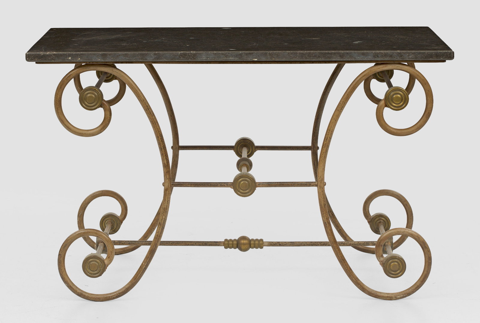 Table de Boulangerie: Eisen, Messing sowie anthrazitfarbener Marmor. Gestell auf großen, gegeneinander gestellten Voluten, durch schmale Stege verbunden. Rechteckige Deckplatte. H. 74 cm. 125 cm x 75 cm. Provenienz: