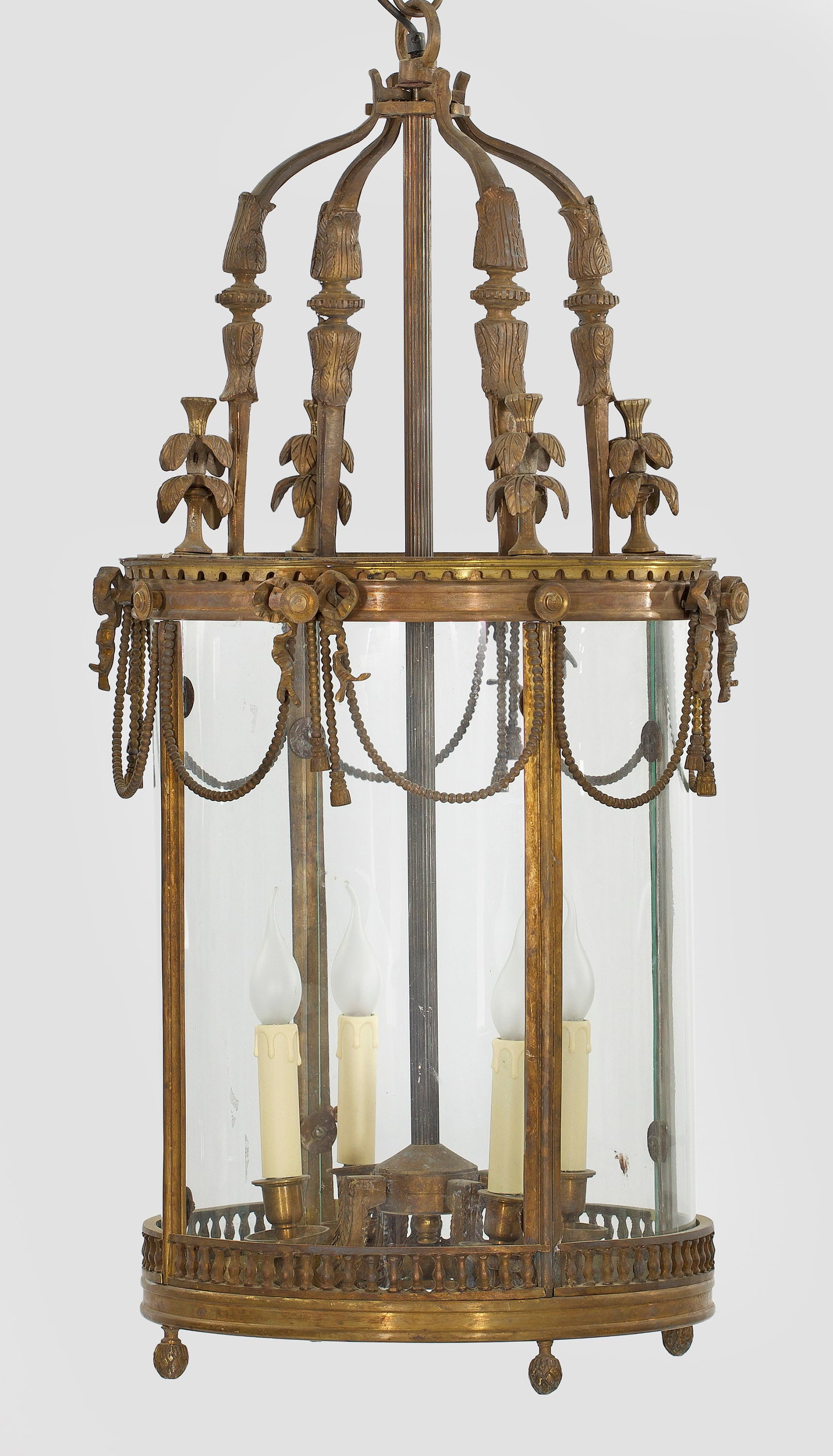Große Deckenampel: 4-flg.; Bronze und farbloses Glas. Zylinderförmiger Korpus aus geraden Streben, umgeben von schmalen, schleifenbekrönten Festons aus Perlschnüren. In der Mitte schlanker Schaft als Träger für Leu