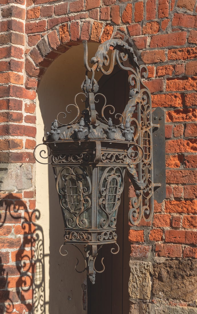 Paar große Wandlaternen im Barockstil: 1-flg.; Schmiedeeisen. Balusterförmiger, sich konisch weitender Korpus aus volutenartig angelegten Stegen mit Glaseinsätzen sowie flacher, kuppelförmiger oberer Abschluss mit Balusterbekrönungen. 