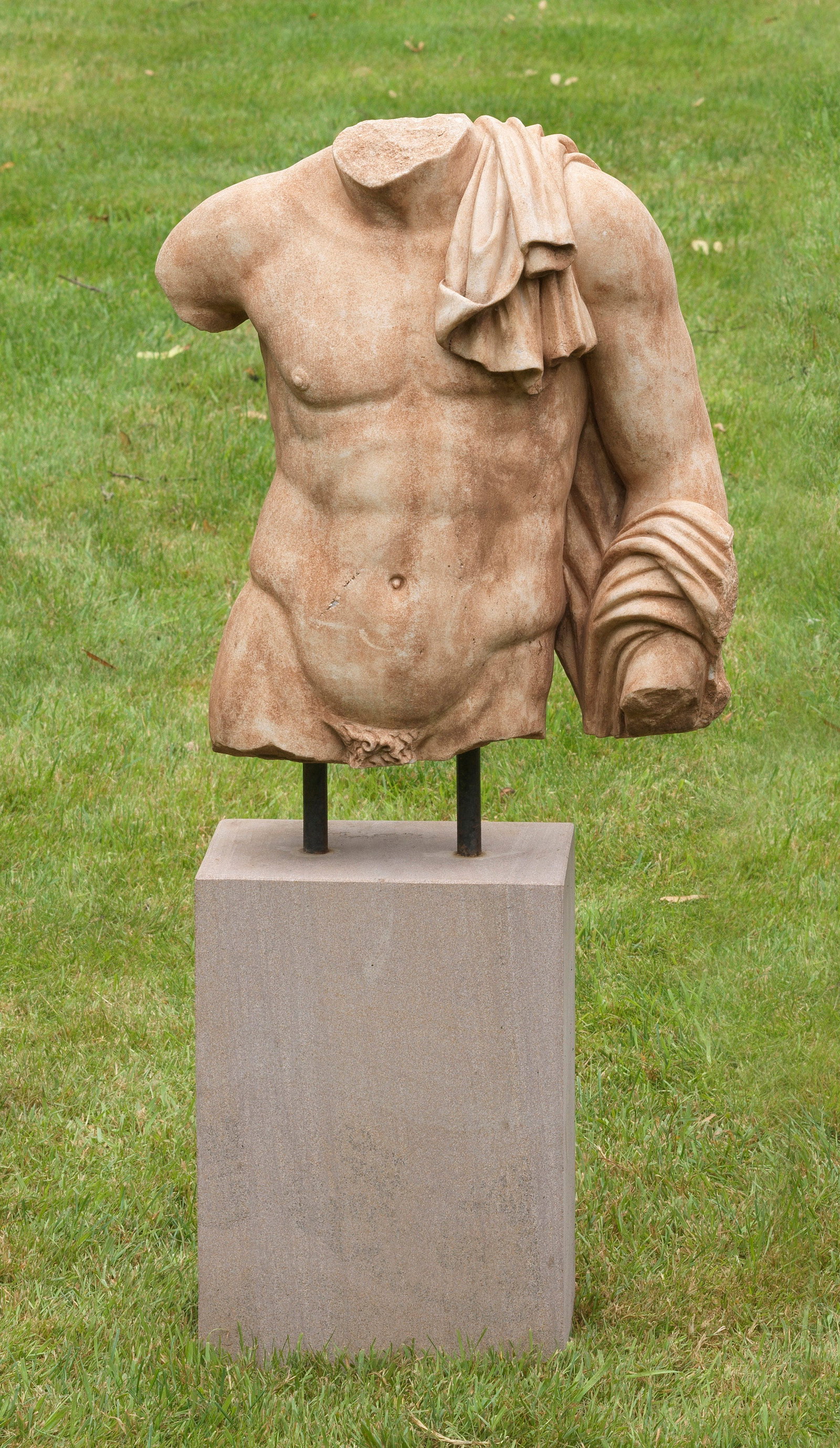 Italienischer Bildhauer: (Tätig im 20. Jh) Römischer Torso Rötlich-brauner Marmor auf hochrechteckigem Travertinsockel. Muskulöser Oberkörper, der lediglich Anklänge seines Umhangs sichtbar werden lässt und wohl auf di