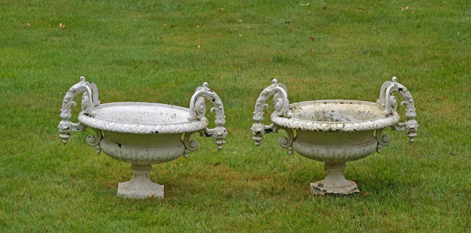 Paar kleine Gartenvasen: Gusseisen, weiß lackiert. Über gefußter Plinthe balusterförmiger, godronierter Korpus mit weit überfallendem Rand. Seitliche blattreliefierte, teilw. architektonisch gegliederte Handhaben mit Vol
