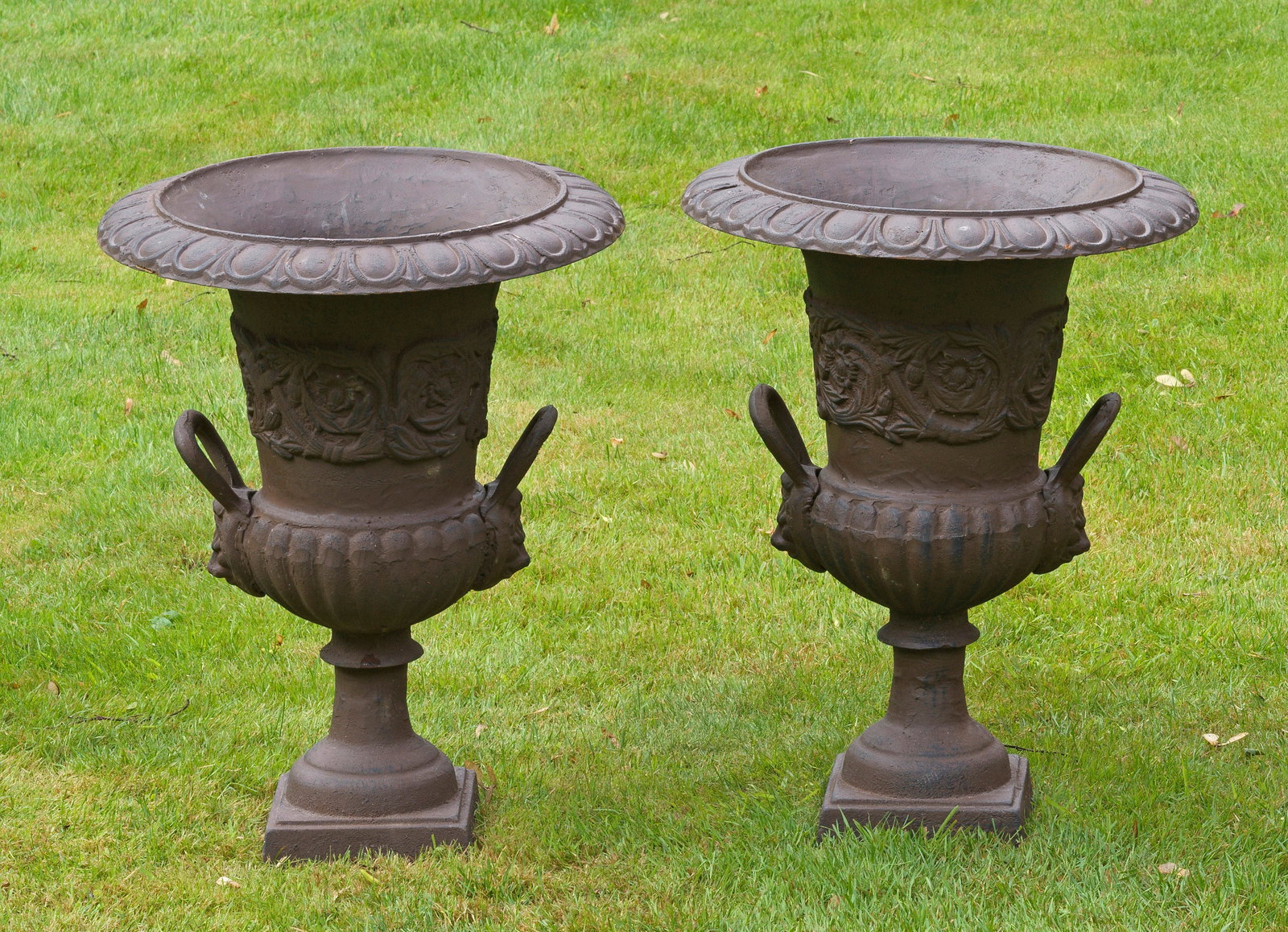 Paar Gartenvasen: Gusseisen. Über quadratischer Plinthe, balusterförmiger, teilw. godronierter Korpus, seitlich mit gebogten Henkeln. Umlaufend der Wandung breiter Fries aus eingerollten Blattvoluten. Weit vorkragend