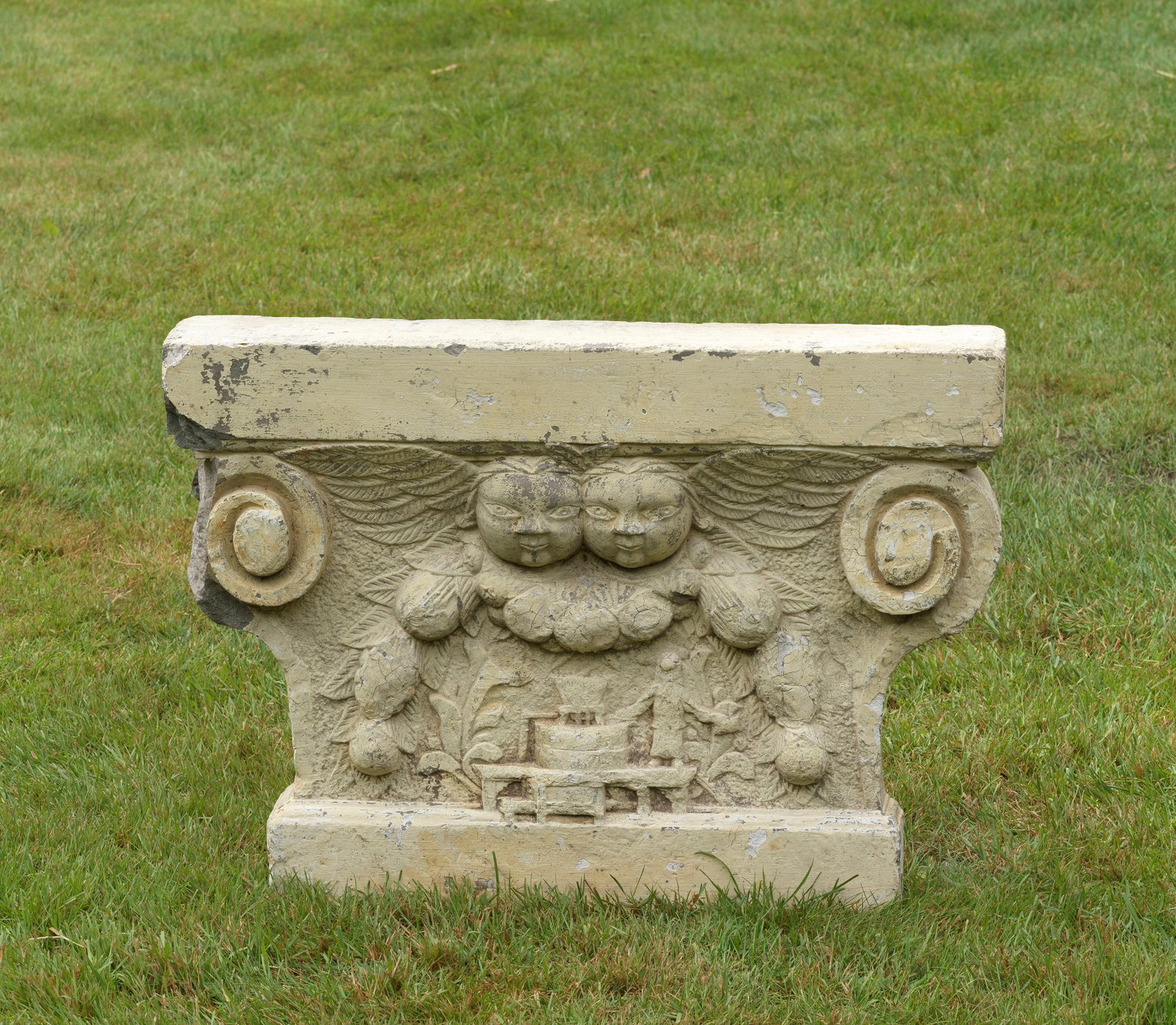 Barock-Ofenstein: Heller Sandstein. Basis für einen Ofen. Rechteckig eingezogener, durch seitliche Voluten und Gesims gegliederter Korpus. Im Relief gearbeitete Darstellung zweier Engel, eine figürliche Szenerie aus 