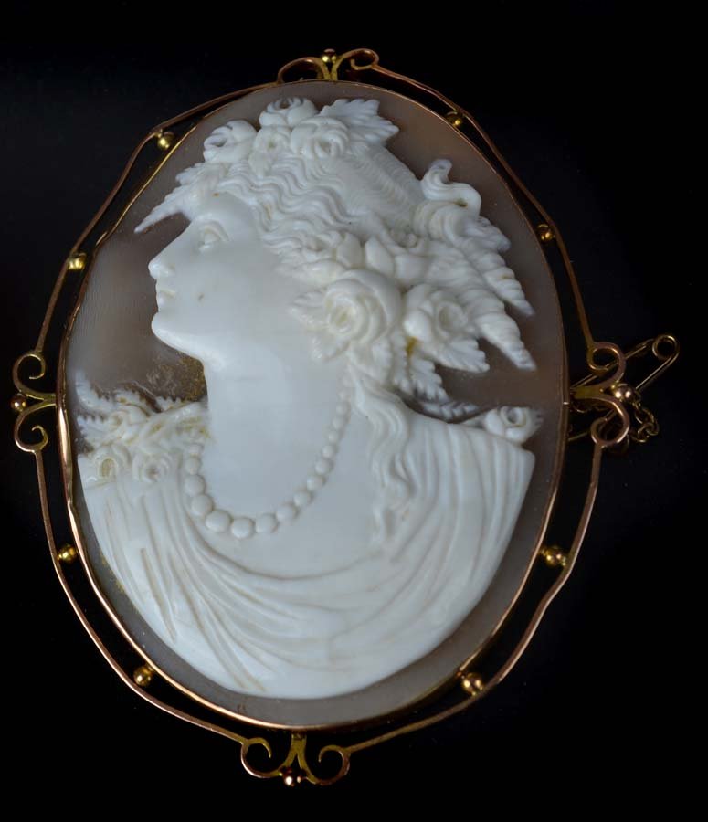 An antique shell cameo gold mounted brooch, c1890, the: An antique shell cameo gold mounted brooch, c1890, the cameo well carved with the profile of a classical maiden with flowers in her hair in a 9ct yellow gold beaded openwork frame, cameo 5.5cm max.