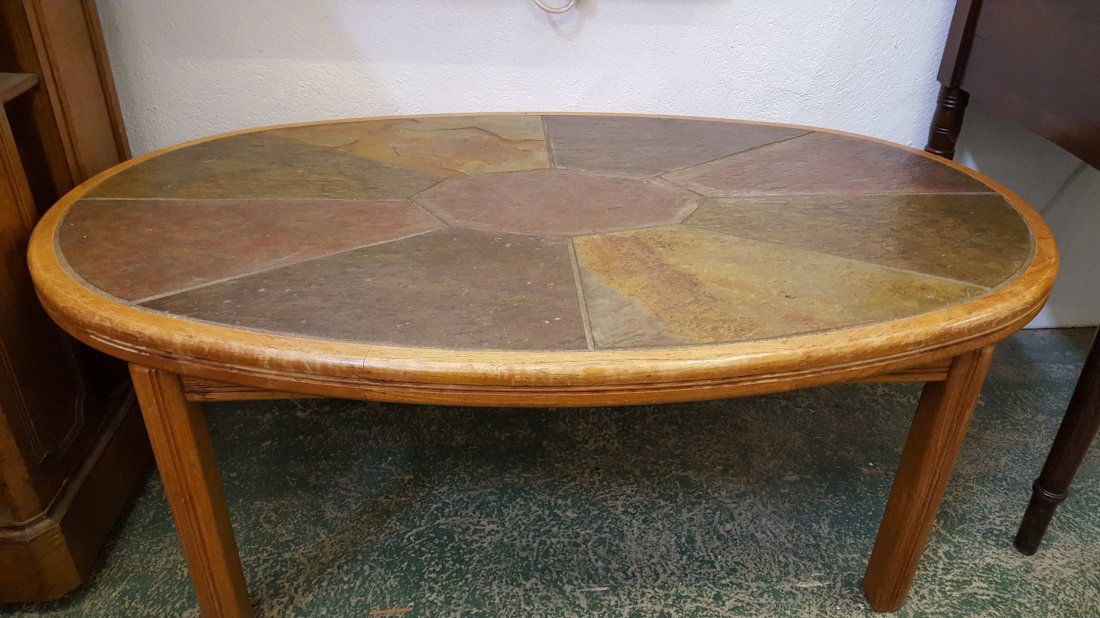 A Haslev (Danish) oval oak frame coffee table, the top: A Haslev (Danish) oval oak frame coffee table, the top inset with natural stone, circular metal disc label to underside, 110cm max oval