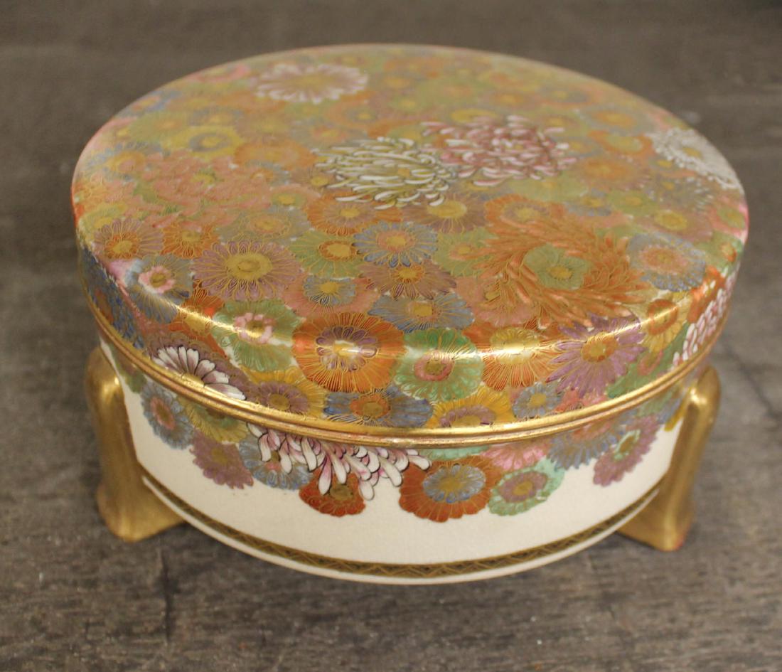 A Satsuma Covered Box, 1900: A Satsuma Covered Box, 1900glazed ceramic, signed, 7.5 in. dia. x 3.75 in. h.Of circular form on wedge shaped feet decorated in an allover pattern of Chrysanthemum, the interior with butterflies.