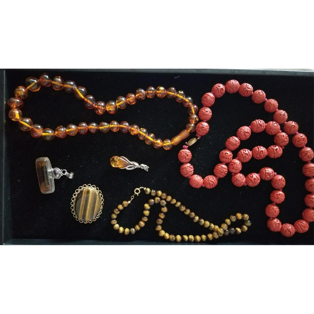 Group Lot of Jewelry Including Chinese Cinnabar: Group Lot of Jewelry Including Chinese Cinnabar Necklace, Amber Beaded Necklace Tiger Eye Beaded Necklace, Tiger Eye Brooch & 2 Sterling Silver Mounted Amber Pendants. Condition: Generally Good Condit
