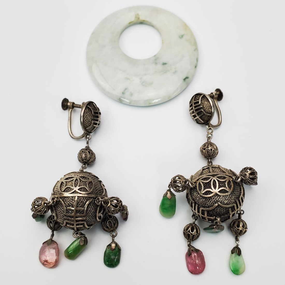Pair of Chinese Silver/Jade Earrings & a Pendant: Pair of Chinese Silver, Jade, and Hard Stone Earrings Along w/ a Jade Pendant. Condition: Generally Very Good. Earrings Have Some Minor Tarnishing. Dimensions: Each Earring H-2.75". Pendant Dia-1.9".