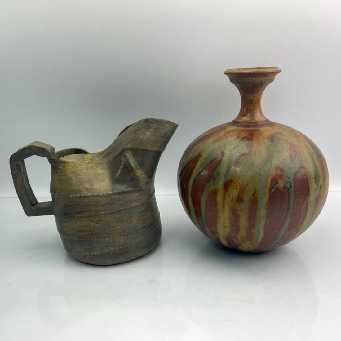 Lot of 2 Signed Pottery Items: Lot of 2 Signed Pottery Items Including a Pitcher by Barbara Hanselman & a Vase by Bill Jackson. Condition: Both Generally Very Good. Dimensions: Vase-H-9" x L-9" (Handle to Spout). Provenance: From t