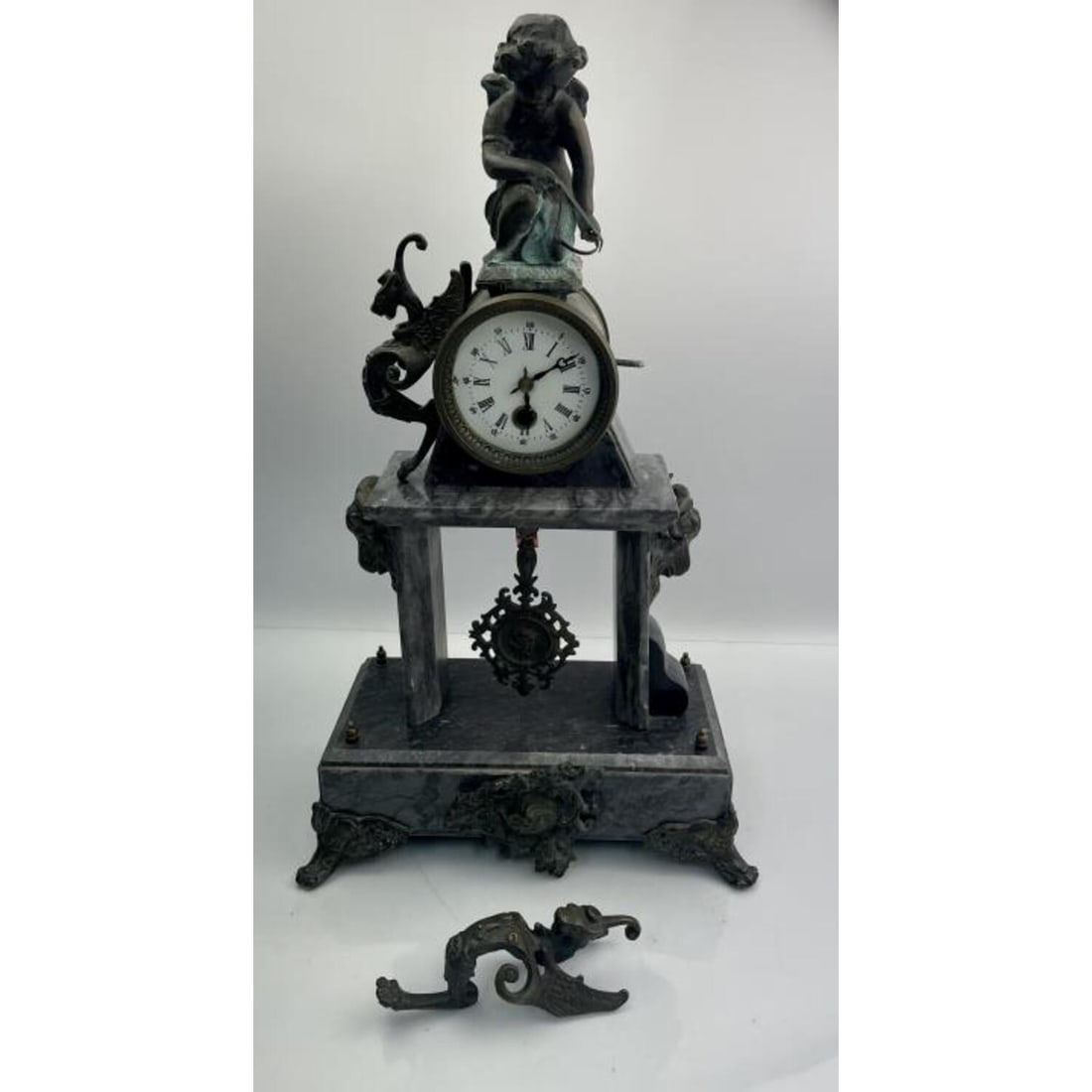 Bronze Mantel Clock with Cherub Motif on Marble: Bronze Mantel Clock with Cherub Motif on Marble Base. Condition: Generally Good, Some Oxidation. Winged Motif on Side of Clock Needs to be Re-Screwed. Chip on the Corner of the Marble. We Cannot Guara