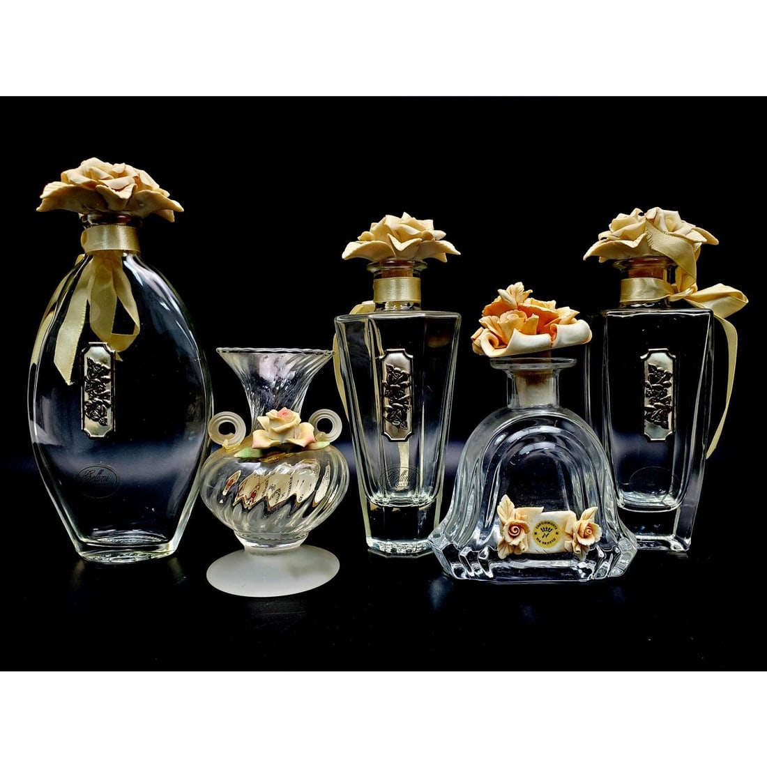 5 Cellini Collection Glass Items w/ Capodimonte: Lot of 5 Cellini Collection Glass Items w/ Capodimonte Porcelain Decorations. There are 4 Perfume Bottles & 1 Vase. Condition: Generally Very Good. Dimensions: Tallest 8.25". Provenance: From a Long I