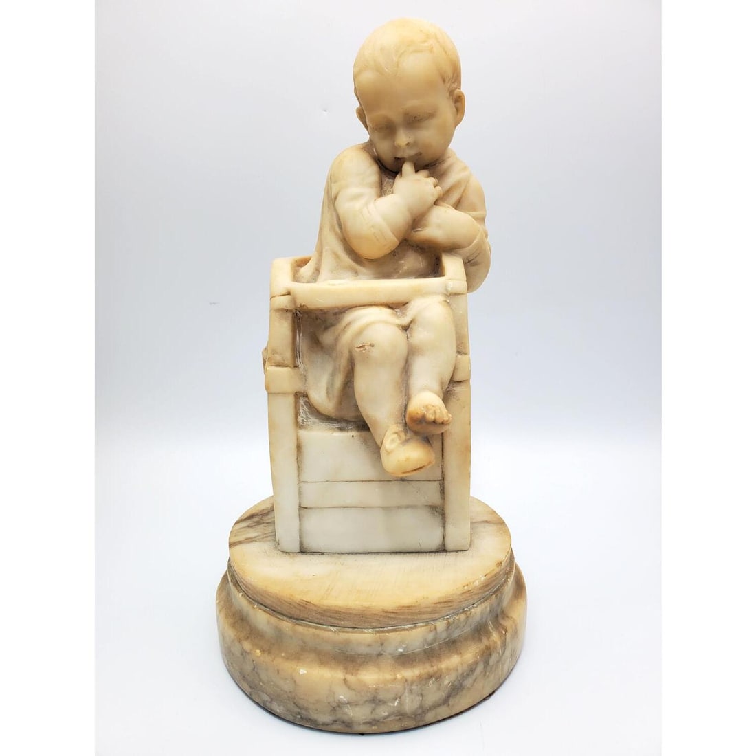 Antique Alabaster Sculpture of Child in Highchair: Antique Alabaster Sculpture of a Child in a Highchair. Apparently Unsigned. Condition: Generally Good. Dimensions: H-12" x Dia. of Base-6.5". Provenance: From a Long Island, NY Home. Please note the a